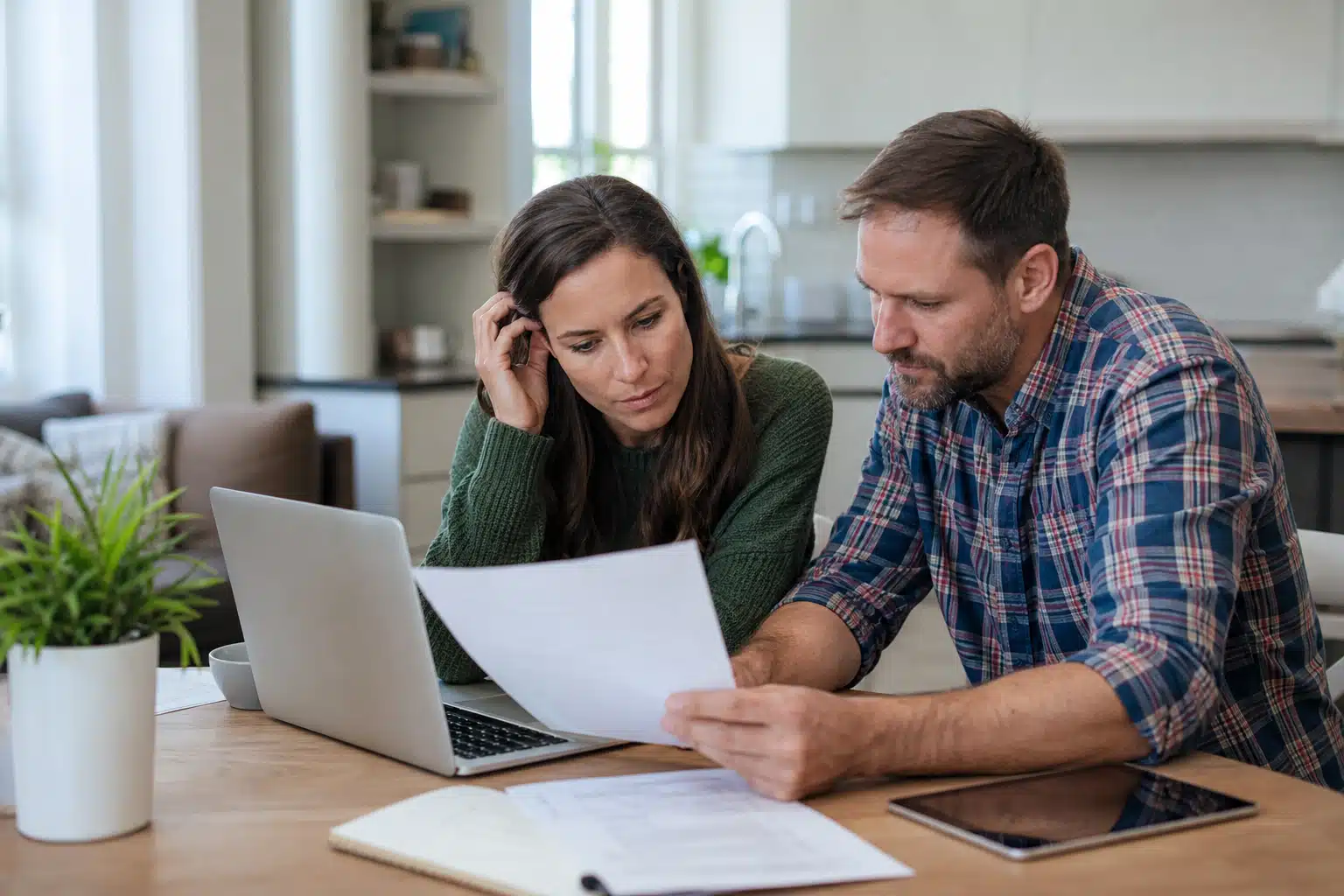 Couple examinant des documents financiers devant ordinateur